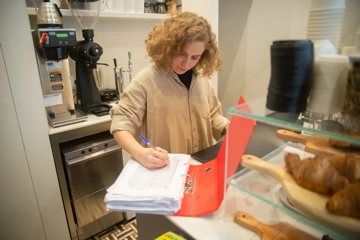 Een ondernemer doet de administratie achter de toonbank van haar café