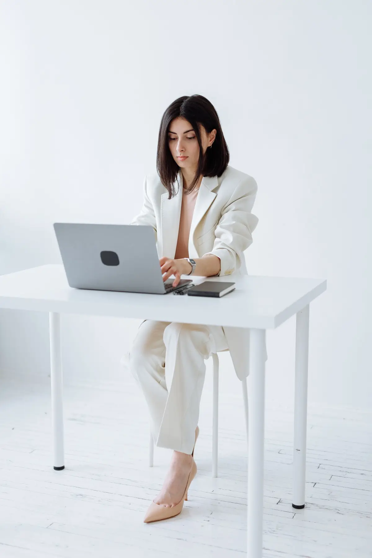 Een vrouw in een witte blazer werkt op haar laptop